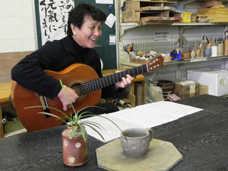 成形後のうつわを前に ギターを弾く橋本勇夫さん